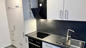 Een moderne keuken met witte kastjes, een roestvrijstalen spoelbak en een zwart fornuis.