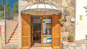 A stone building with a wooden door and shutters, a staircase to the left, and a map on the wall. - 1 bedroom nice apartment in Budoni (Budoni)