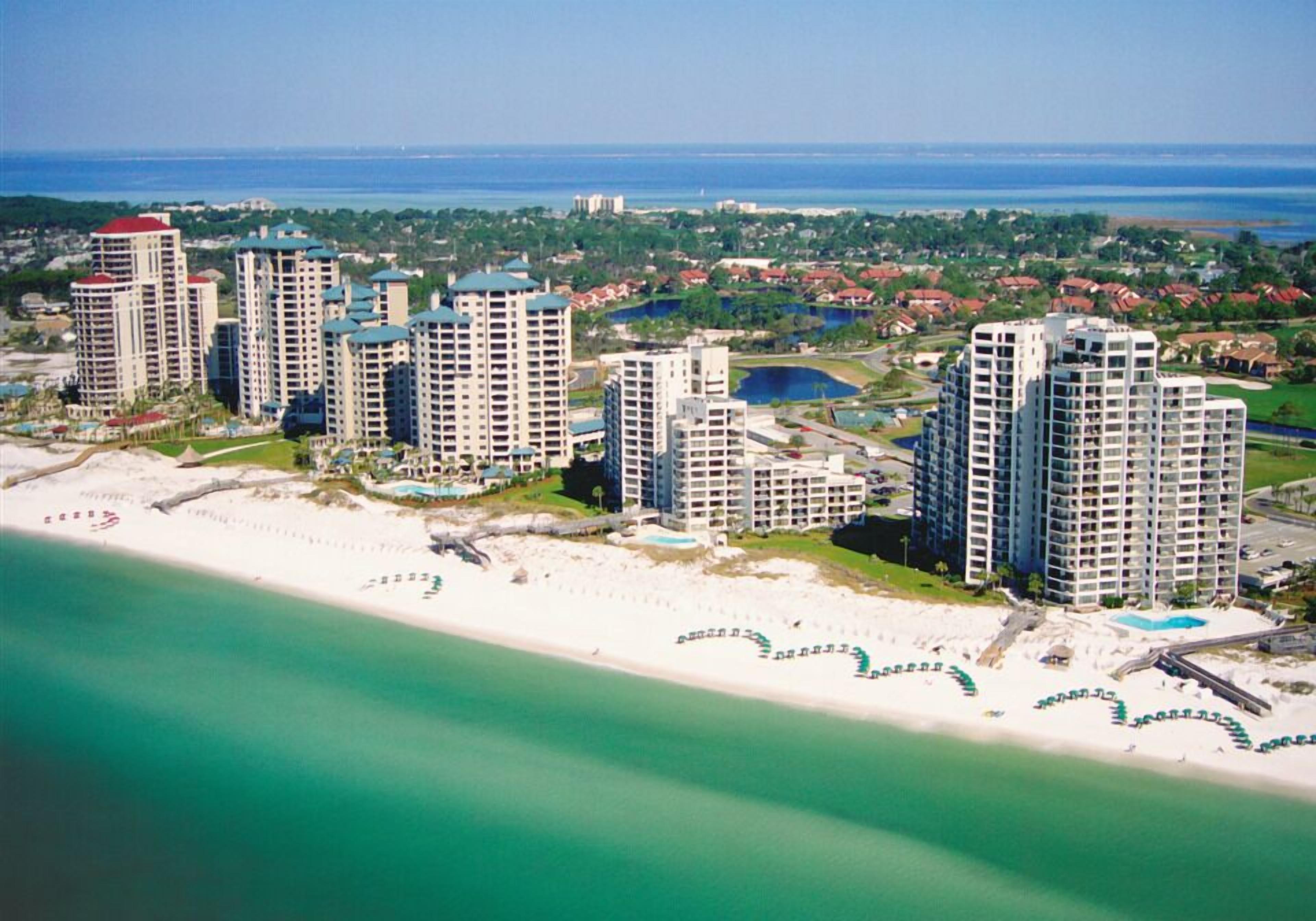 Eine Küstenlandschaft mit Hochhäusern, einem Strand und einem Yachthafen.