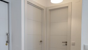A hallway with two white doors, a wooden floor, and a hanging light fixture. - Spacious and bright apartment 700m from the beach (VC)