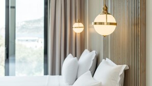 A modern hotel room with a large bed, two bedside lamps, a view of the outdoors, and a wooden panel wall. - Bodrum Astrid Hotel  (Bodrum)