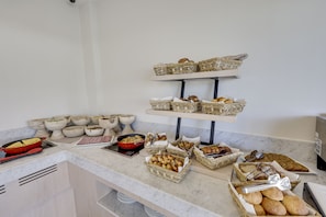 A buffet setup with various food items displayed in baskets and bowls on a marble countertop. - Bodrum Astrid Hotel  (Bodrum)