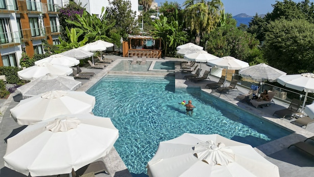 A pool area with lounge chairs and umbrellas, a bar, and a view of the sea. - Bodrum Astrid Hotel  (Bodrum)