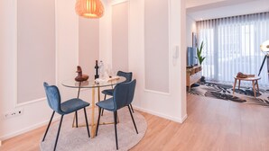 A modern dining area with a round table, two blue chairs, and a unique orange pendant light.