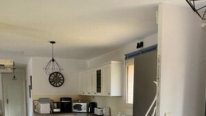 Una cocina amplia con gabinetes blancos, microondas, cafetera y mesa de fútbol.