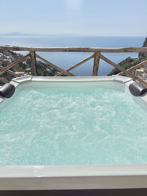 A hot tub with a view of the sea and a mountainous landscape.