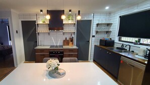 A modern kitchen with a central island, built-in shelves, and a large window.