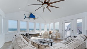 Ein geräumiges Wohnzimmer mit einer großen Couch, einem Kamin und Blick auf den Ozean.