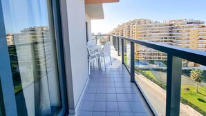 A balcony with a view of high-rise buildings, a tiled floor, and a railing.