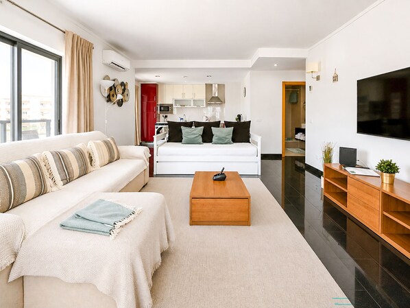 A modern living room with a sofa, coffee table, and a TV. - Flat Praia Rocha Tower Sunset (Portimão)