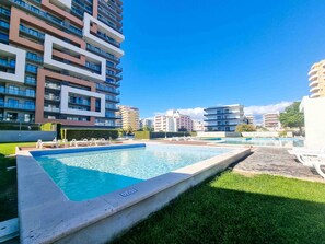 A swimming pool with lounge chairs, surrounded by modern apartment buildings. - Flat Praia Rocha Tower Sunset (Portimão)