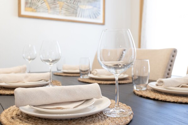 A dining table set with plates, glasses, and a napkin.