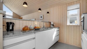 Une cuisine moderne avec des panneaux en bois, des comptoirs en granit et des luminaires suspendus.