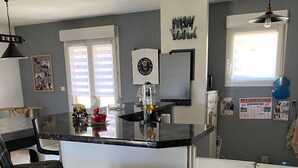 A kitchen with a bar area, a refrigerator, and a window with blinds. - Rooms in house (Gercourt-et-Drillancourt)