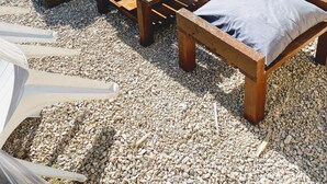 An outdoor seating area with two cushioned sofas and a wooden coffee table, surrounded by gravel. - Rooms in house (Gercourt-et-Drillancourt)