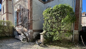A courtyard with a gravel path, a tree, and a building with brick and stucco walls.