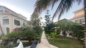 Un espace extérieur aménagé en patio, avec des meubles de jardin, des palmiers et un jardin bien entretenu.