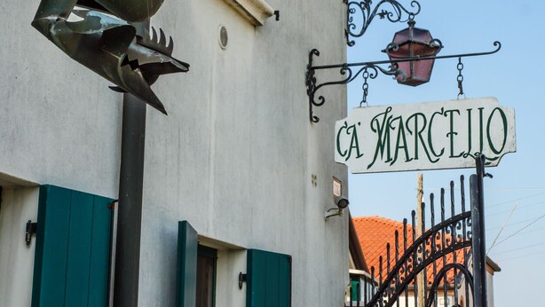 A street sign reading "CA' MARCELLO" mounted on a building with a metal awning and a black wrought iron gate. - Apartment for 2 people surrounded by greenery! (Mira)