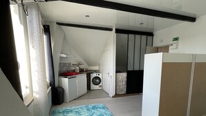 A compact kitchen with a washing machine, a small sink, and a countertop with various items. - Fully Equipped Furnished Design (Poissy)