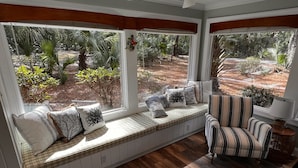 A room with a built-in bench along a large window overlooking a garden.