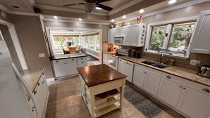 A modern kitchen with white cabinets, a wooden island, and a view of the outdoors.