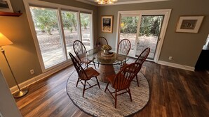 A dining area with a round table, chairs, and a chandelier.