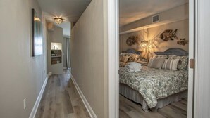 Habitación de hotel con cama, mesita de noche, lámpara y una obra de arte colgada en la pared.