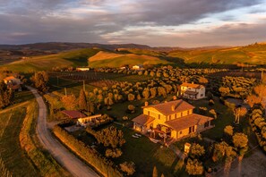 An aerial view of a rural landscape with rolling hills, a vineyard, and a few scattered buildings. - Ribusieri Country House (Cinigiano)