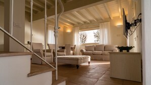 A spacious living room with a high ceiling, a staircase, and a view of the outdoors. - Ribusieri Country House (Cinigiano)