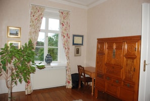 A room with a window, a wooden cabinet, a chair, and a radiator.