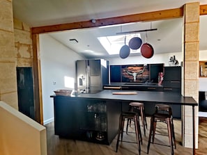 Uma cozinha moderna com uma ilha central, banquetas de bar e um claraboia.