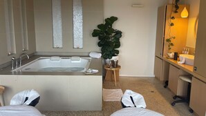 Ein modernes Badezimmer mit einer großen Badewanne, einem Spiegel und einer Zimmerpflanze.