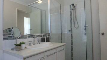 Een bad/douchecombinatie, een haardroger, handdoeken, toiletpapier