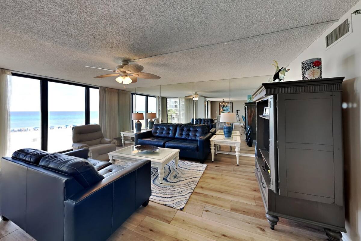 A spacious living room with a large sofa, a coffee table, and a view of the ocean.