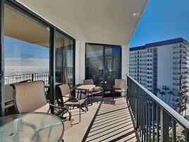A balcony with a glass door, a table, and chairs.