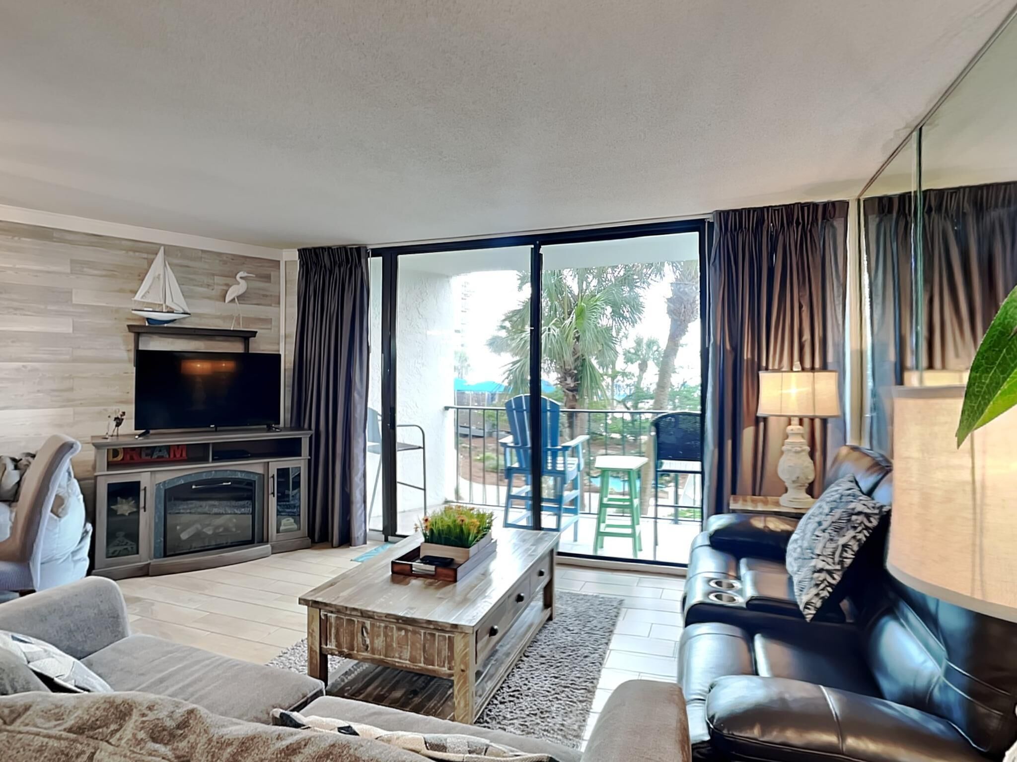 A modern living room with a fireplace, sofa, and a balcony with outdoor furniture.