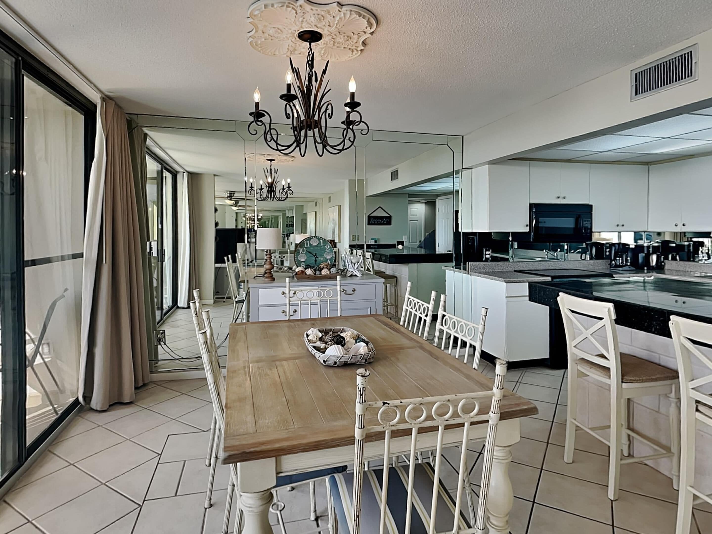 Uma cozinha espaçosa com uma mesa de jantar de madeira, cadeiras brancas e uma bancada grande.