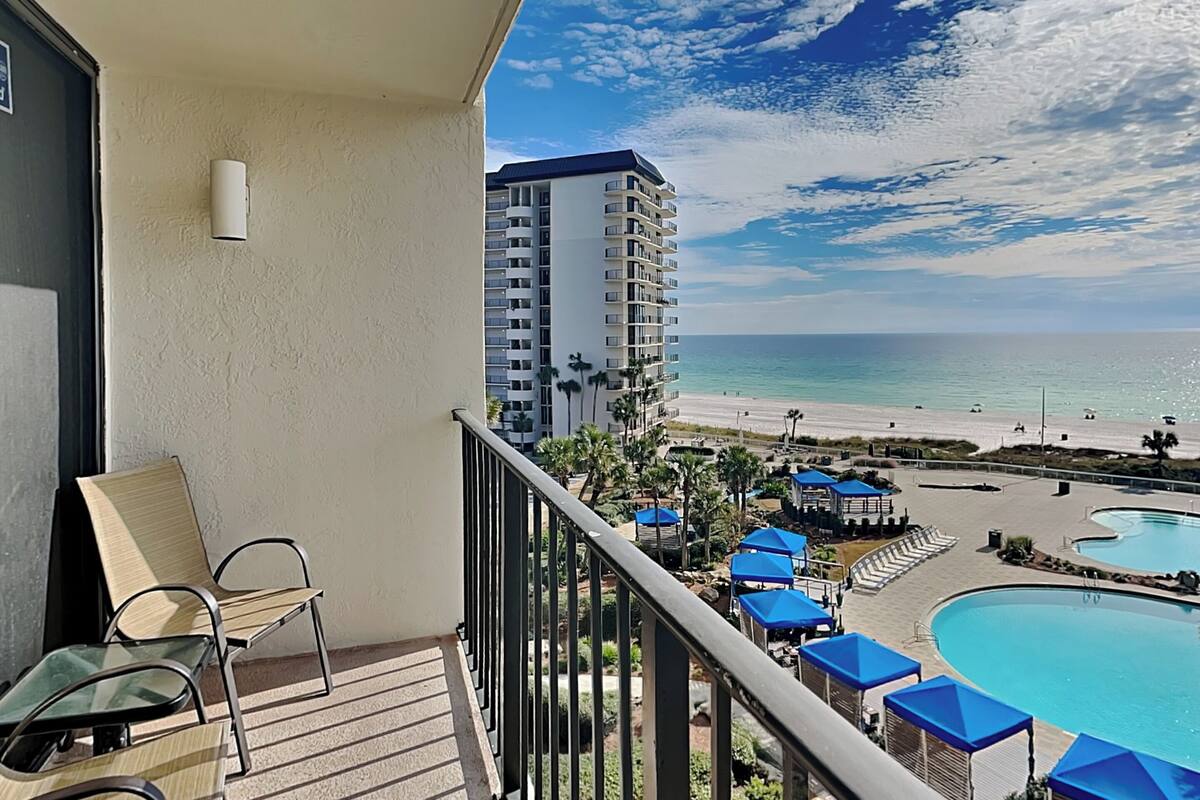 A balcony with a view of a beach and a pool.