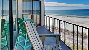 Un balcón con vista a la playa, que incluye una mesa y sillas.