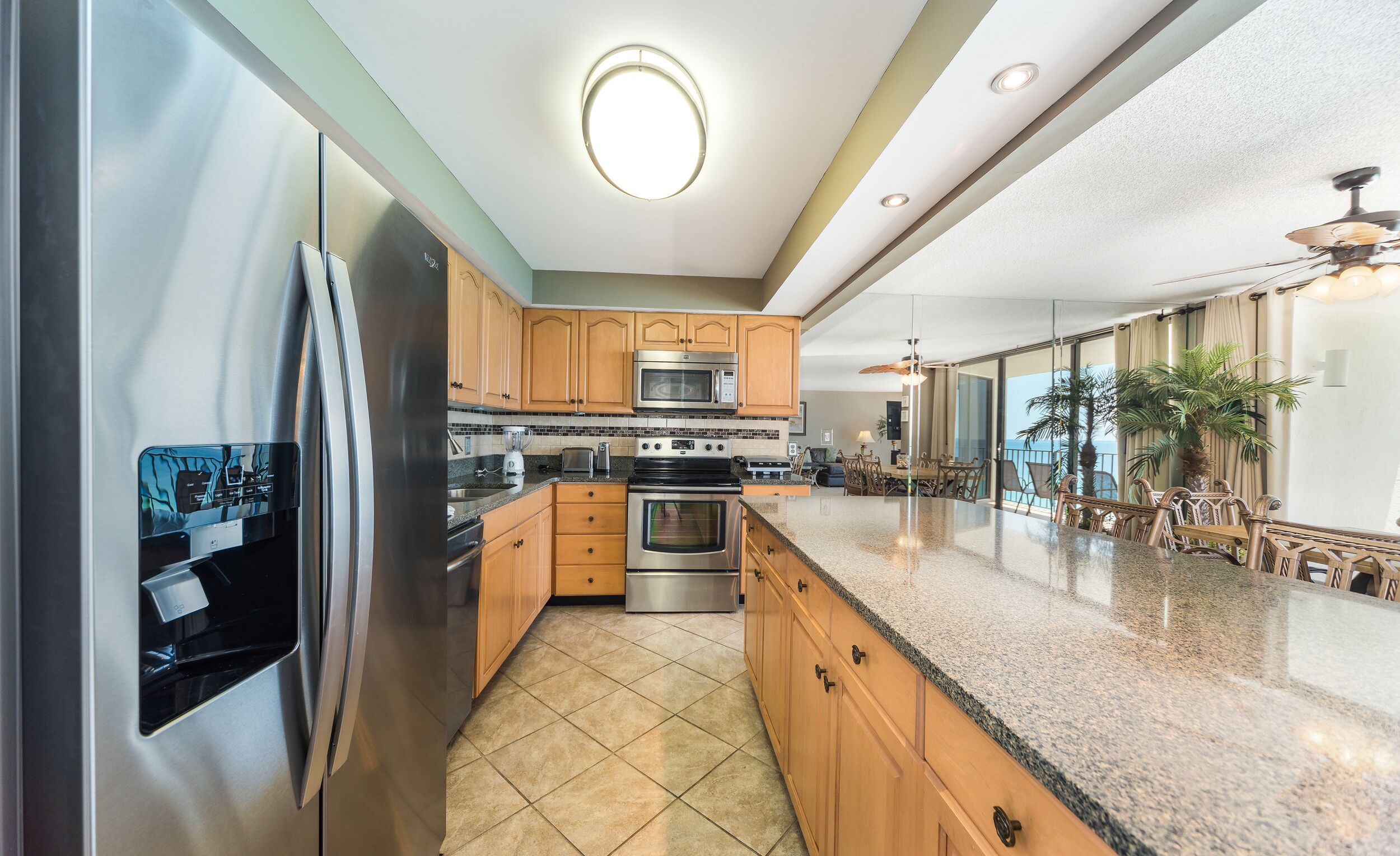 A modern kitchen with stainless steel appliances, wooden cabinets, and a granite countertop.