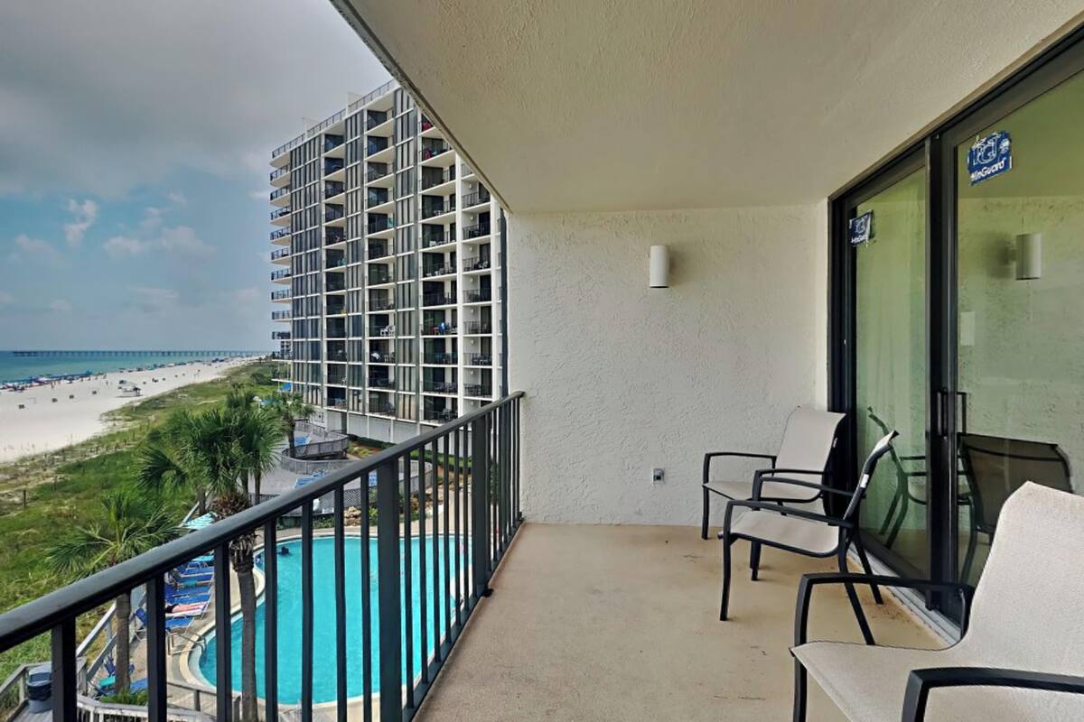 A balcony with a view of a beach and a pool.