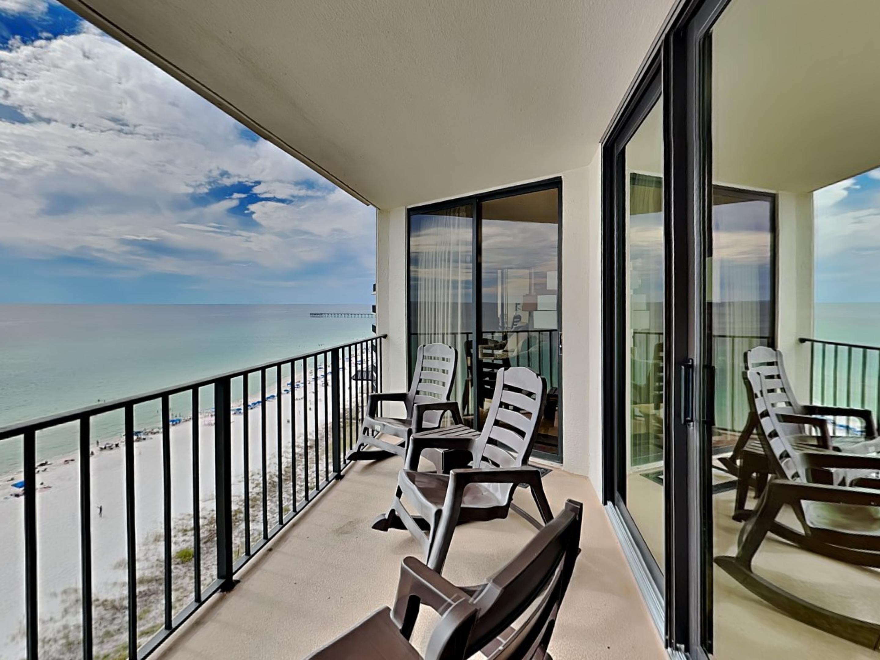 A balcony with beach views, furnished with lounge chairs and a table.