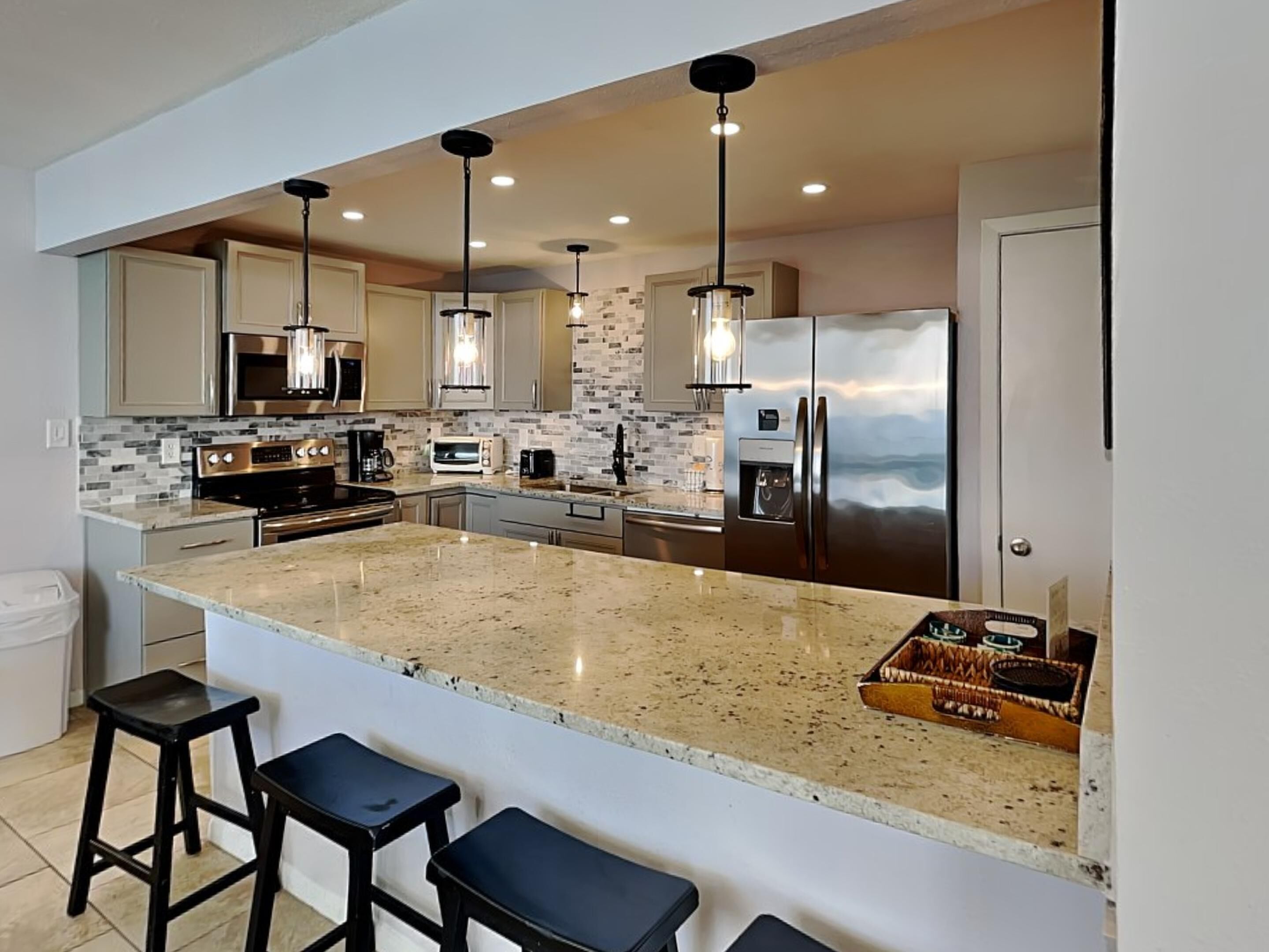 A modern kitchen with granite countertops, stainless steel appliances, and pendant lighting.