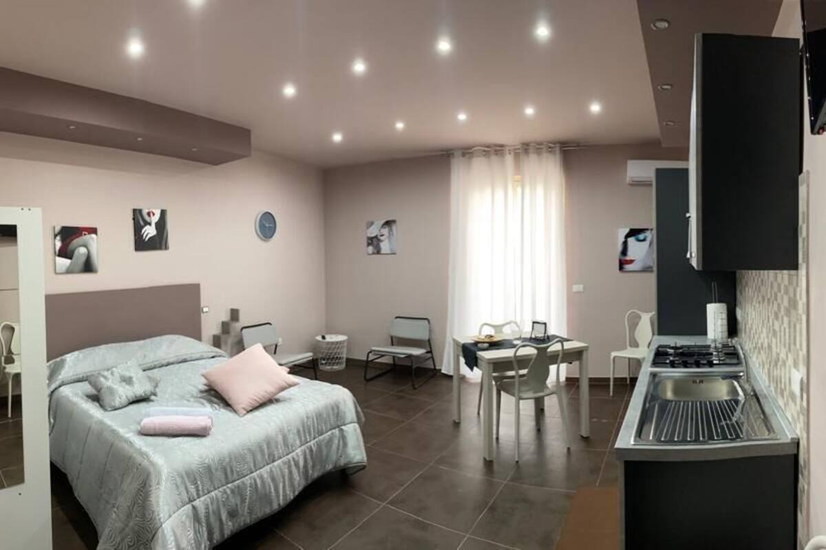 Ein modernes Hotelzimmer mit Bett, Schreibtisch, Stuhl, einer Küchenzeile und einem Badezimmer.