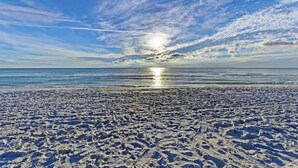 A beach with footprints leading to the water, a clear sky, and the sun reflecting on the water. - AMI Moana Villa 3-minute walk to the beach plus heated pool, grill, beach gear (Holmes Beach)