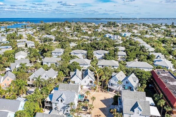 A coastal residential area with houses surrounded by palm trees and a view of the ocean.