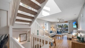 A spacious living area with a staircase, a sofa, a coffee table, and a TV. - AMI Moana Villa 3-minute walk to the beach plus heated pool, grill, beach gear (Holmes Beach)