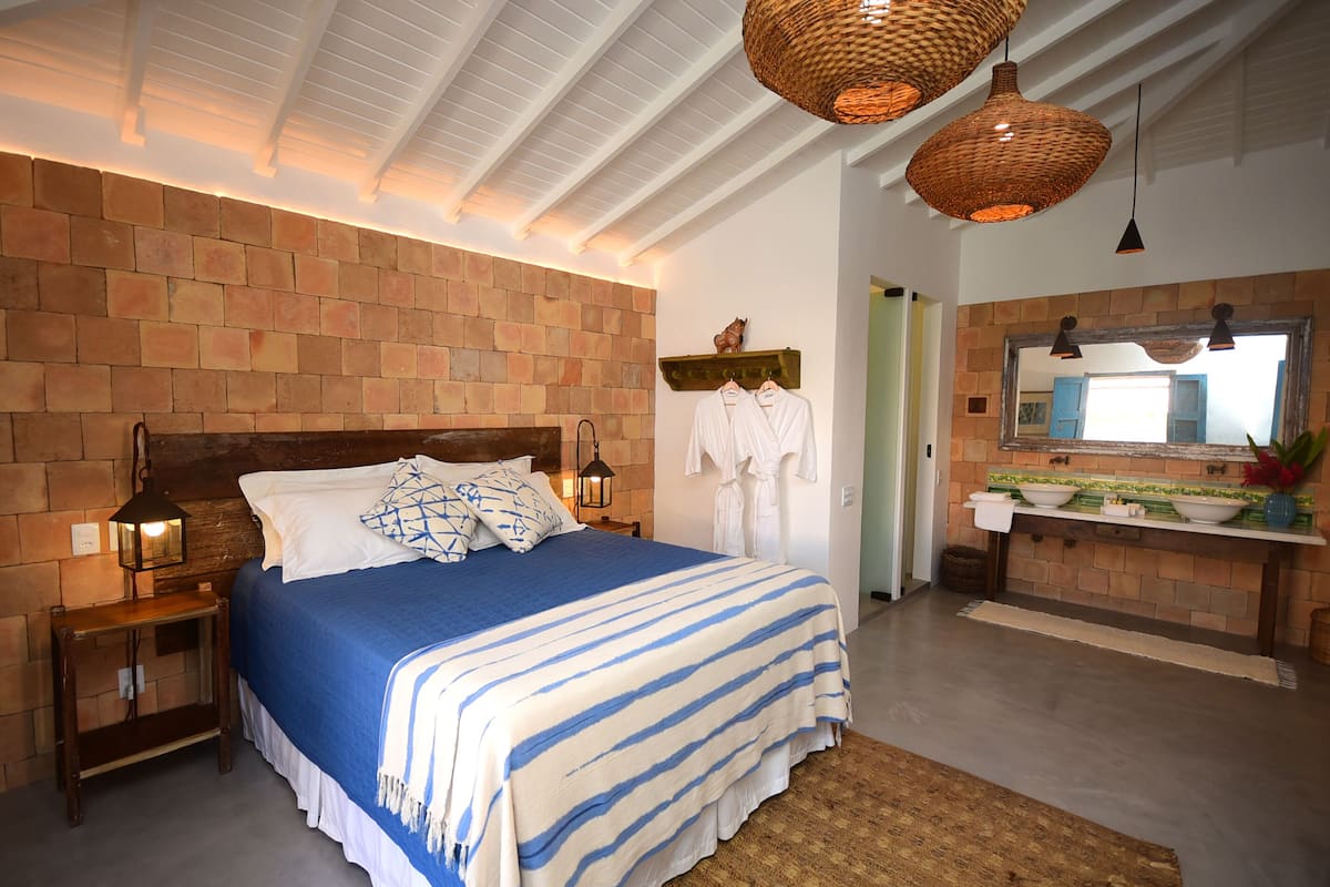 Une chambre avec un mur en briques, un lit en bois, une table de chevet et un luminaire suspendu.