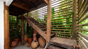 Una escalera de madera de estilo rústico, rodeada de macetas con plantas y una valla de bambú.