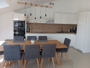 A modern kitchen with white cabinets, a wooden countertop, and a dining area with a wooden table and chairs.